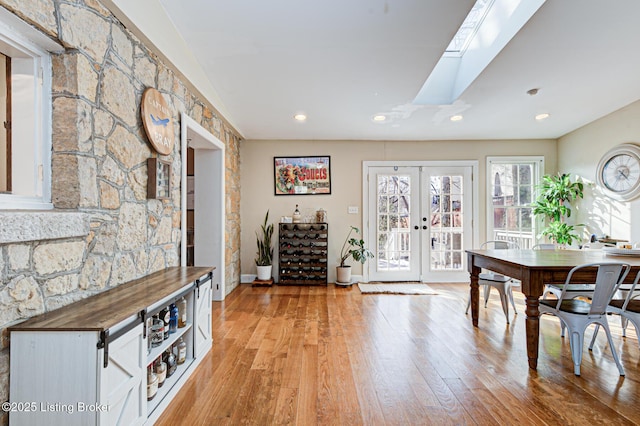 dining room featuring french doors, a skylight, and light hardwood / wood-style floors