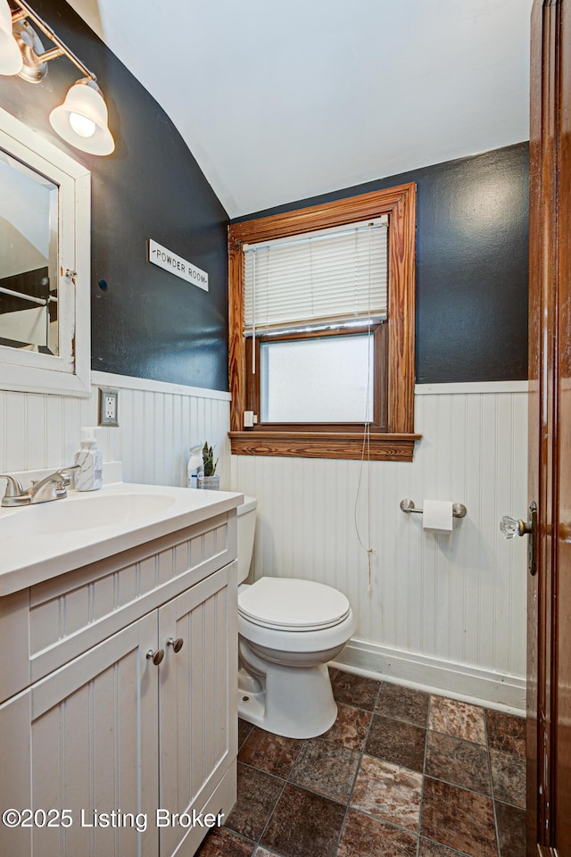 bathroom with lofted ceiling, vanity, and toilet