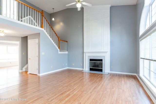 unfurnished living room with ceiling fan, light hardwood / wood-style flooring, a wealth of natural light, and a premium fireplace