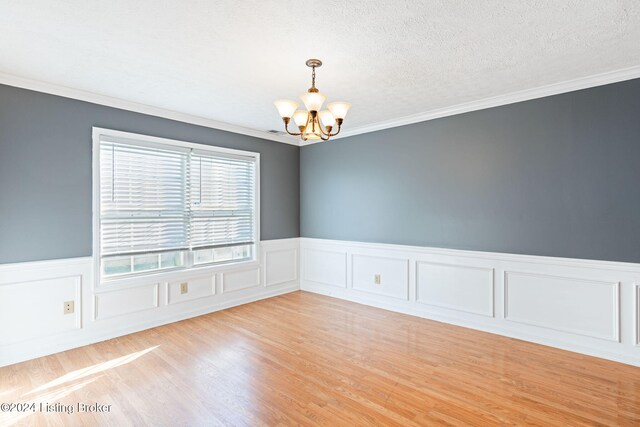 empty room with a textured ceiling, an inviting chandelier, and crown molding