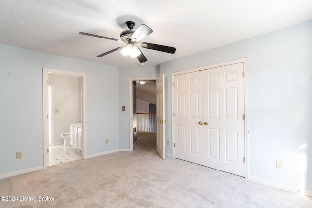 unfurnished bedroom featuring a closet, ensuite bathroom, ceiling fan, and light colored carpet