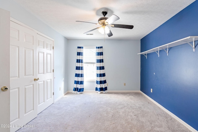 unfurnished bedroom with ceiling fan, light carpet, and a textured ceiling