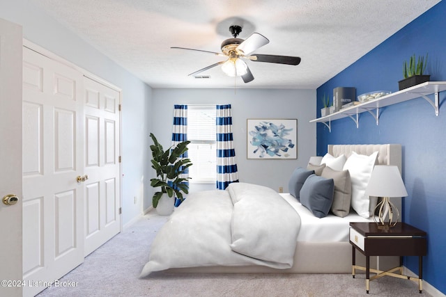 carpeted bedroom with ceiling fan and a textured ceiling