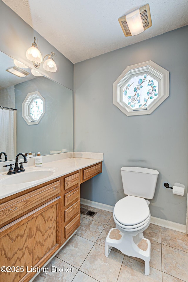 bathroom with toilet, vanity, tile patterned flooring, and plenty of natural light