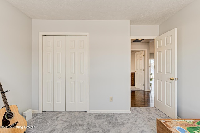 unfurnished bedroom featuring a closet, a textured ceiling, and light colored carpet