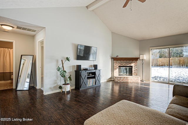 living room with hardwood / wood-style flooring, a textured ceiling, a brick fireplace, ceiling fan, and beamed ceiling