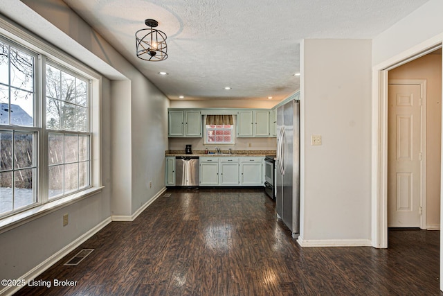 kitchen featuring dark wood-type flooring, a textured ceiling, a chandelier, pendant lighting, and appliances with stainless steel finishes