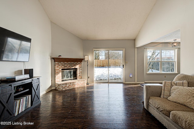 living room with lofted ceiling, dark hardwood / wood-style flooring, a brick fireplace, and a textured ceiling