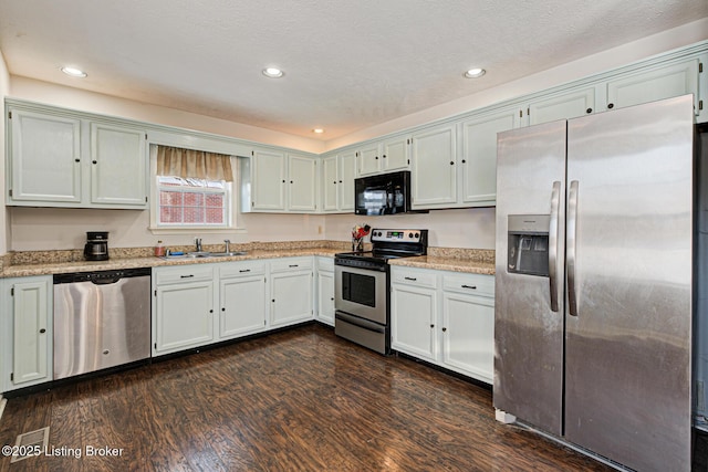 kitchen with stainless steel appliances, light stone countertops, a textured ceiling, dark hardwood / wood-style floors, and sink