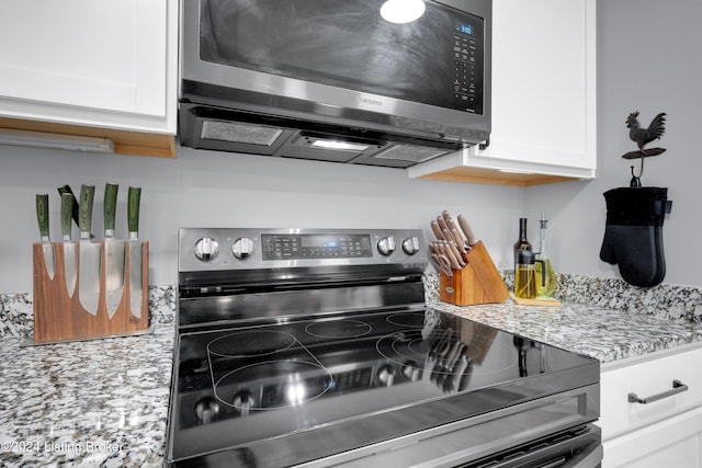 kitchen with white cabinets, light stone counters, and stainless steel electric range