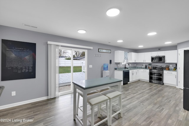 kitchen featuring hardwood / wood-style flooring, sink, white cabinetry, and stainless steel appliances