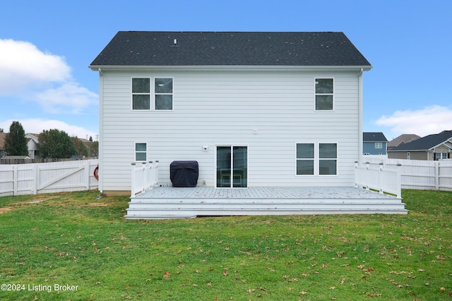 back of property featuring a deck and a lawn