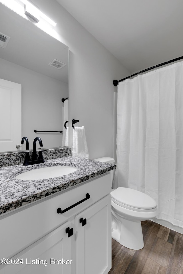 bathroom featuring vanity, wood-type flooring, and toilet