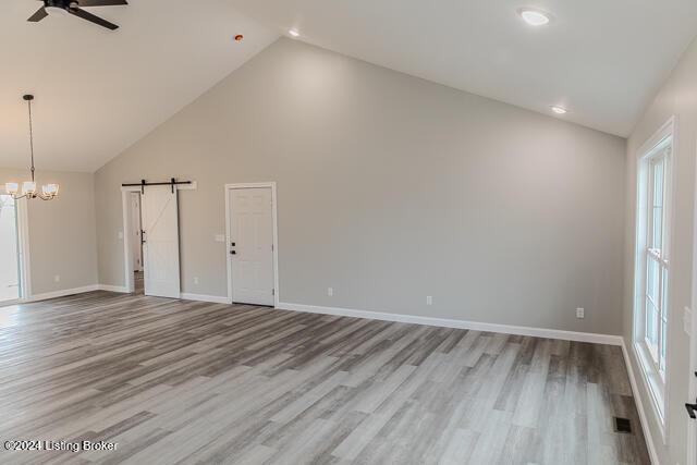 363 S Hamilton Ave, Hanover, IN 47243 - unfurnished living room with a barn door, a ceiling fan, high vaulted ceiling, wood finished floors, and plenty of natural light
