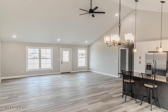 kitchen featuring stainless steel fridge, light wood-type flooring, pendant lighting, high vaulted ceiling, and white cabinets