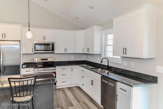 kitchen featuring lofted ceiling, white cabinets, sink, hanging light fixtures, and stainless steel appliances