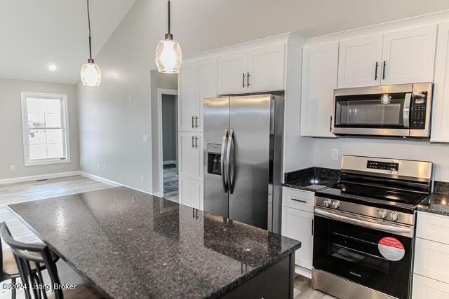 kitchen featuring pendant lighting, a center island, lofted ceiling, white cabinetry, and stainless steel appliances