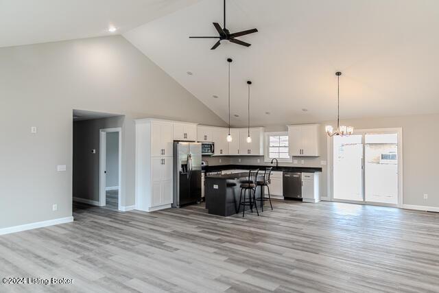 kitchen with white cabinets, appliances with stainless steel finishes, high vaulted ceiling, and a kitchen island