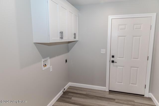 washroom with electric dryer hookup, hookup for a washing machine, cabinets, and light hardwood / wood-style floors