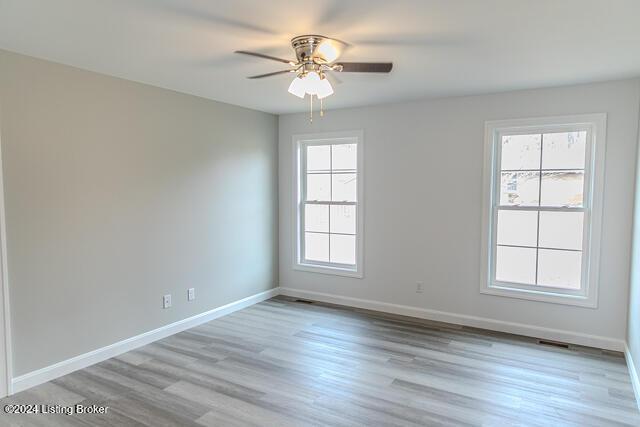 empty room with light hardwood / wood-style floors, a wealth of natural light, and ceiling fan