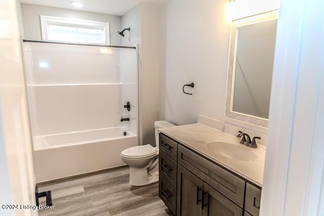 full bathroom with hardwood / wood-style floors, vanity, toilet, and shower / bathtub combination