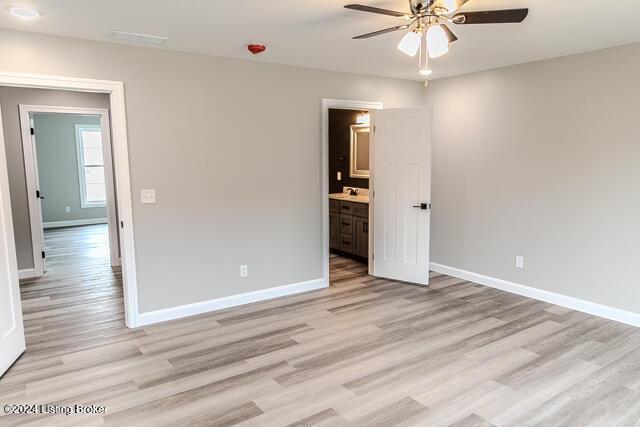 unfurnished bedroom with ceiling fan, ensuite bath, and light hardwood / wood-style flooring