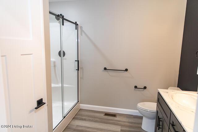 bathroom with vanity, hardwood / wood-style flooring, toilet, and walk in shower