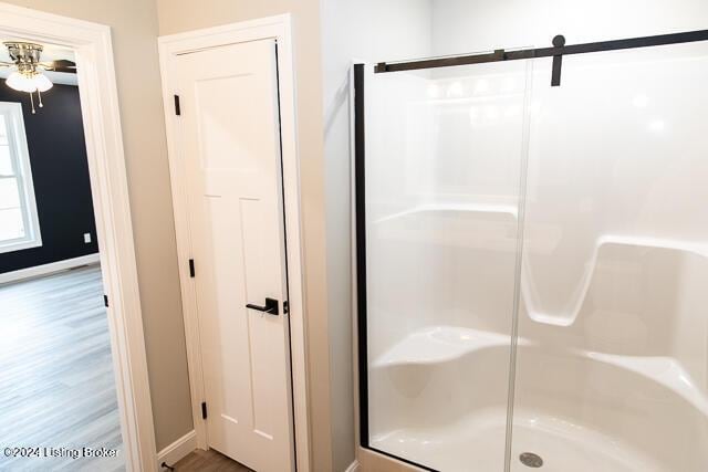 bathroom featuring hardwood / wood-style floors, ceiling fan, and walk in shower