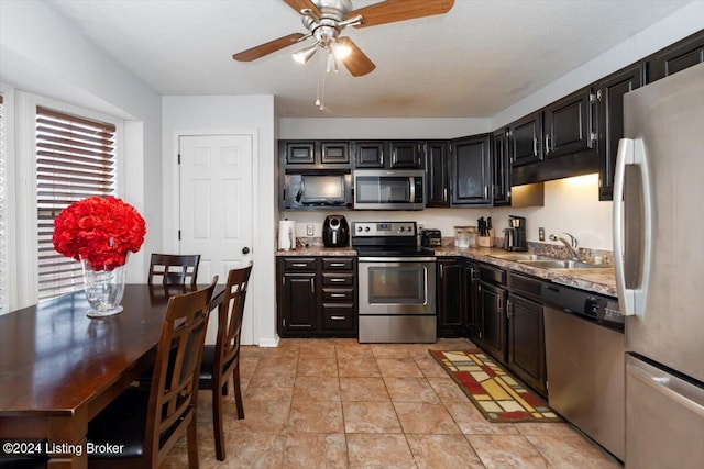 kitchen with stone counters, sink, ceiling fan, a textured ceiling, and stainless steel appliances
