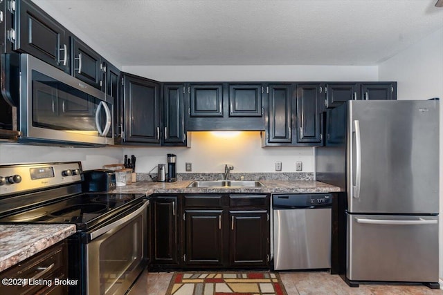 kitchen with a textured ceiling, sink, and stainless steel appliances