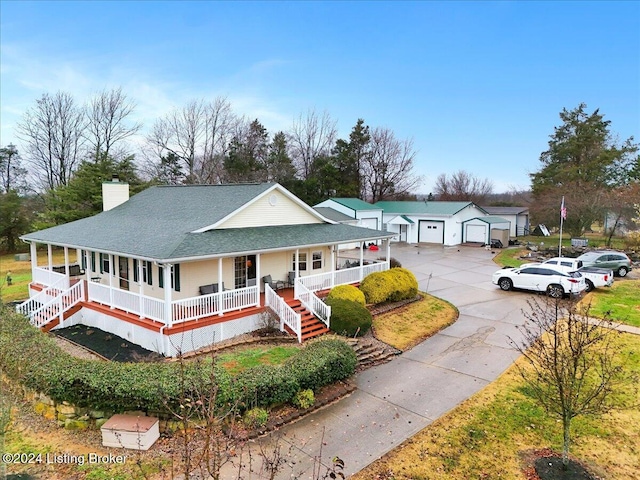 farmhouse inspired home with covered porch, an outbuilding, and a garage