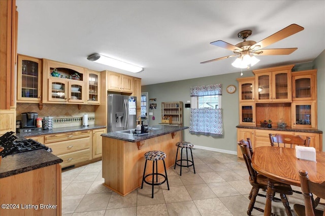 kitchen with decorative backsplash, a kitchen breakfast bar, stainless steel fridge with ice dispenser, a center island, and light tile patterned flooring