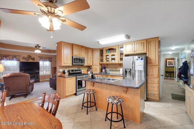 kitchen with sink, stainless steel appliances, backsplash, an island with sink, and a kitchen bar