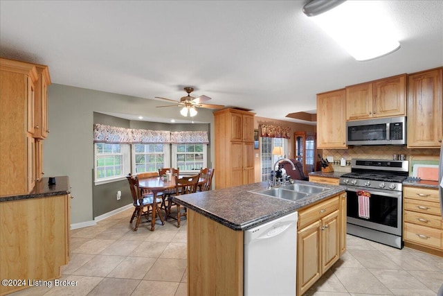 kitchen with tasteful backsplash, stainless steel appliances, ceiling fan, sink, and an island with sink