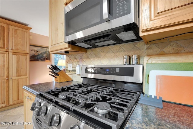 kitchen featuring stainless steel appliances, light brown cabinetry, and tasteful backsplash