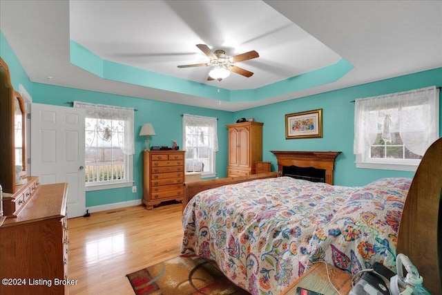 bedroom featuring a raised ceiling, ceiling fan, and light hardwood / wood-style floors