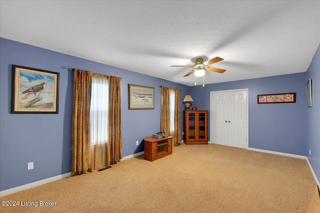 interior space featuring ceiling fan, light colored carpet, and a textured ceiling