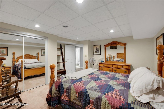 carpeted bedroom with a paneled ceiling and a closet