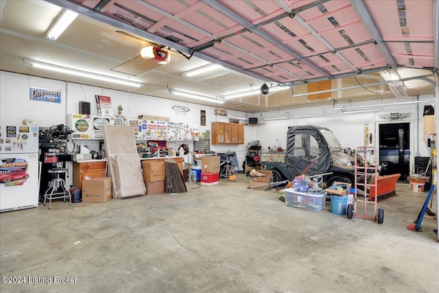 garage with a workshop area, white refrigerator, and a garage door opener