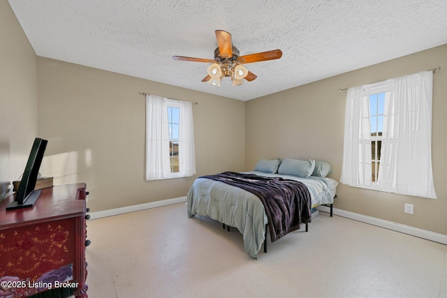 bedroom featuring multiple windows, ceiling fan, and a textured ceiling