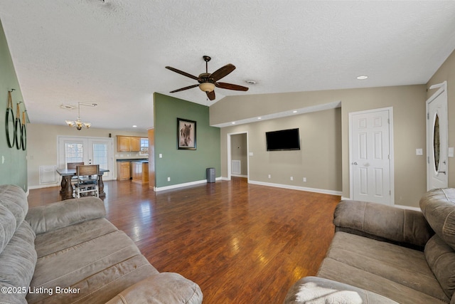 living room featuring ceiling fan with notable chandelier, a textured ceiling, dark hardwood / wood-style floors, and vaulted ceiling