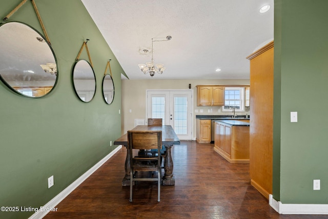 dining space featuring sink, french doors, dark wood-type flooring, and a notable chandelier