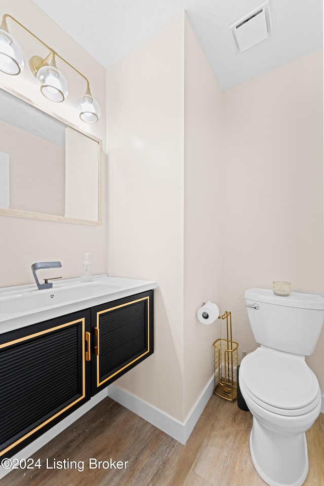 bathroom with toilet, vanity, and hardwood / wood-style flooring