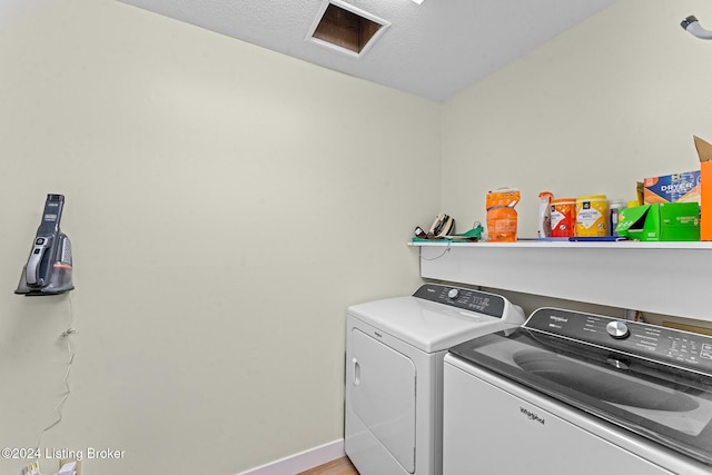 clothes washing area featuring washer and dryer, a textured ceiling, and light hardwood / wood-style flooring