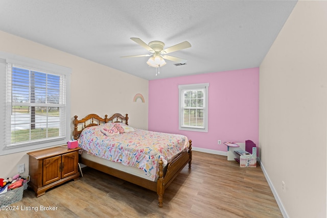 bedroom with ceiling fan, light hardwood / wood-style flooring, and a textured ceiling