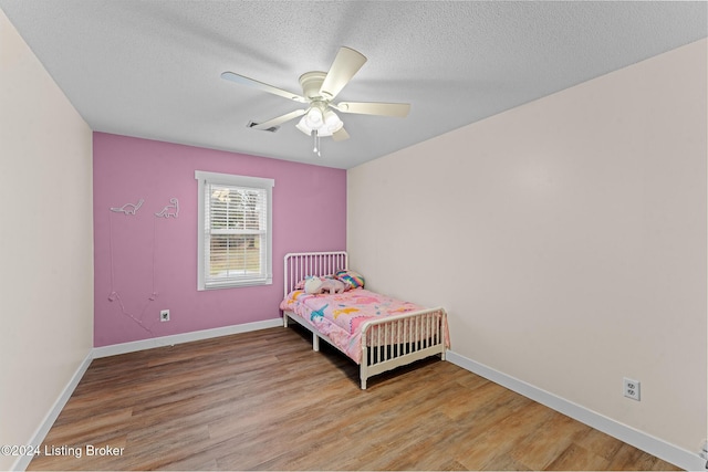 bedroom featuring ceiling fan, a textured ceiling, and light wood-type flooring