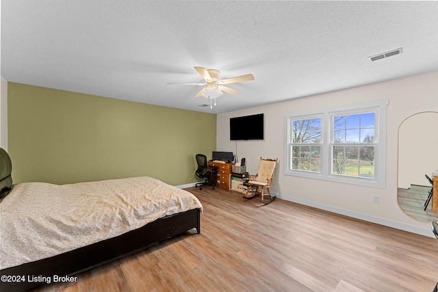 bedroom featuring a textured ceiling, light wood-type flooring, and ceiling fan