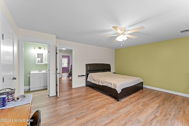 bedroom with ensuite bath, ceiling fan, a textured ceiling, and light wood-type flooring