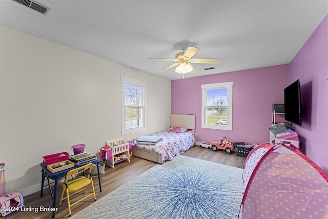 bedroom with light hardwood / wood-style flooring, multiple windows, and ceiling fan