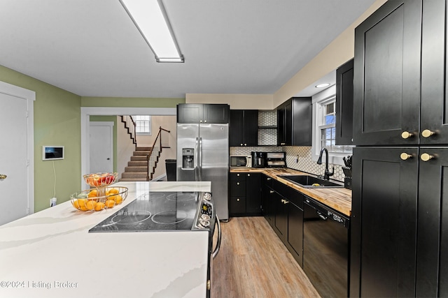 kitchen featuring backsplash, sink, light hardwood / wood-style floors, light stone counters, and stainless steel appliances